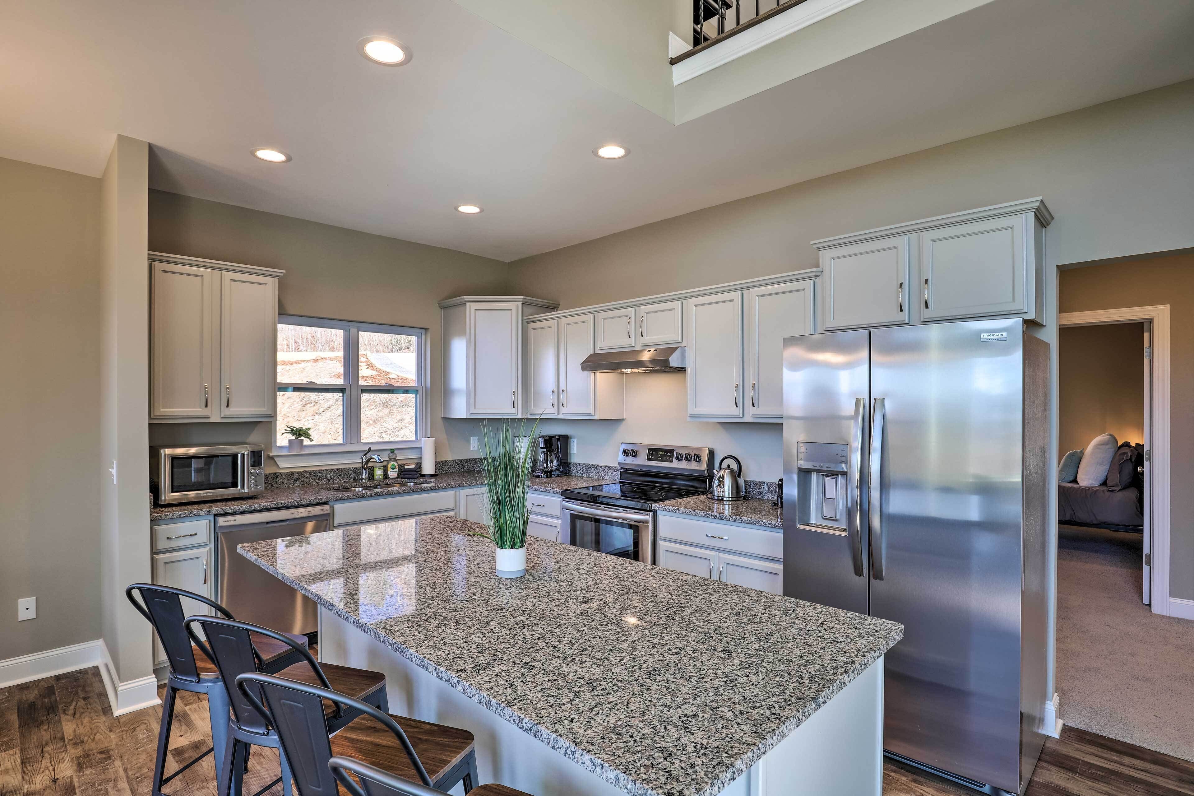 A modern kitchen with granite countertops, stainless steel appliances, and a large island with bar stools.