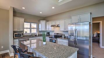 A modern kitchen with granite countertops, stainless steel appliances, and a large island with bar stools.