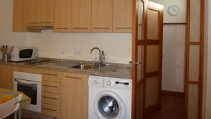 A compact kitchen with wooden cabinets, a microwave, a sink, a dishwasher, and a washing machine. - APARTMENT IN MONACHIL PUEBLO/GRANADA (ANDALUCIA) (Monachil)