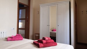 A hotel room with two beds, a wardrobe, and a bathroom visible through a glass door. - APARTMENT IN MONACHIL PUEBLO/GRANADA (ANDALUCIA) (Monachil)