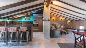 A modern kitchen with a bar area, a dining table, and a cozy seating area with a sofa and armchairs.