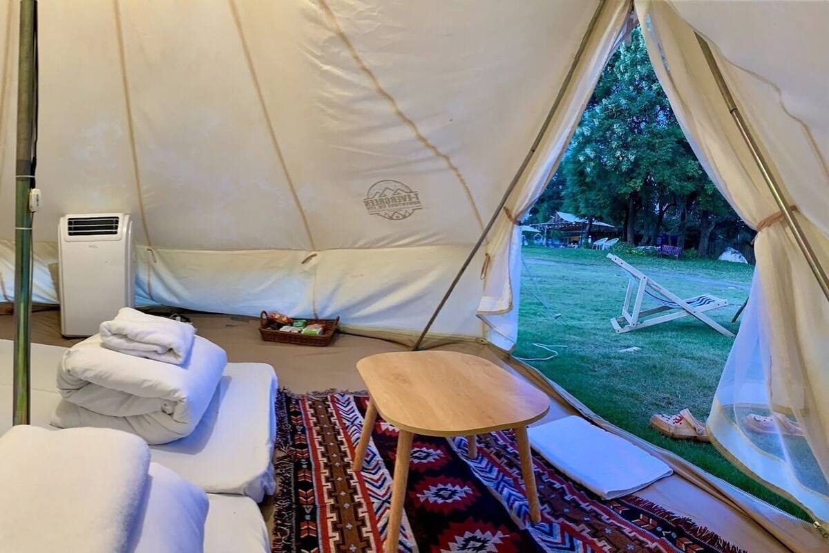 Ein Zelt mit Bett, einem kleinen Tisch und Blick ins Freie.