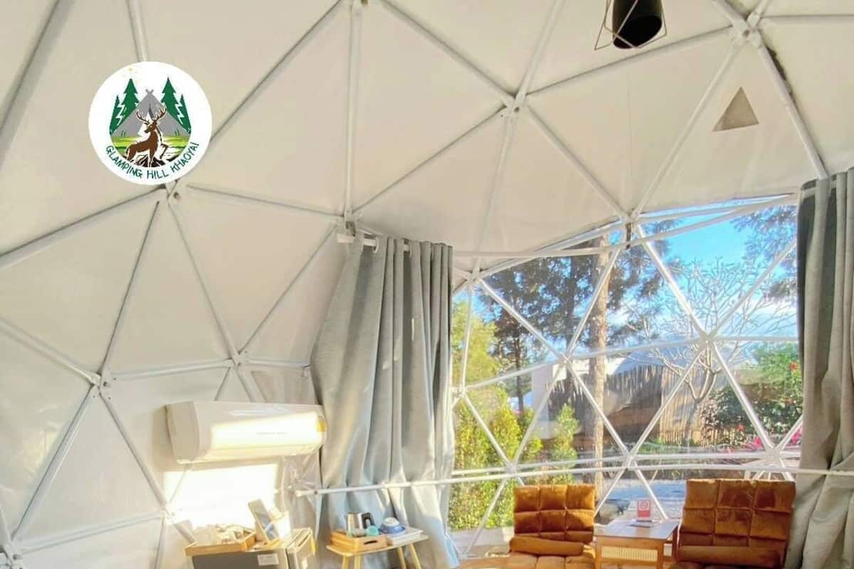 Eine Zelthütte mit Bett, Sitzgelegenheit und Blick ins Freie.