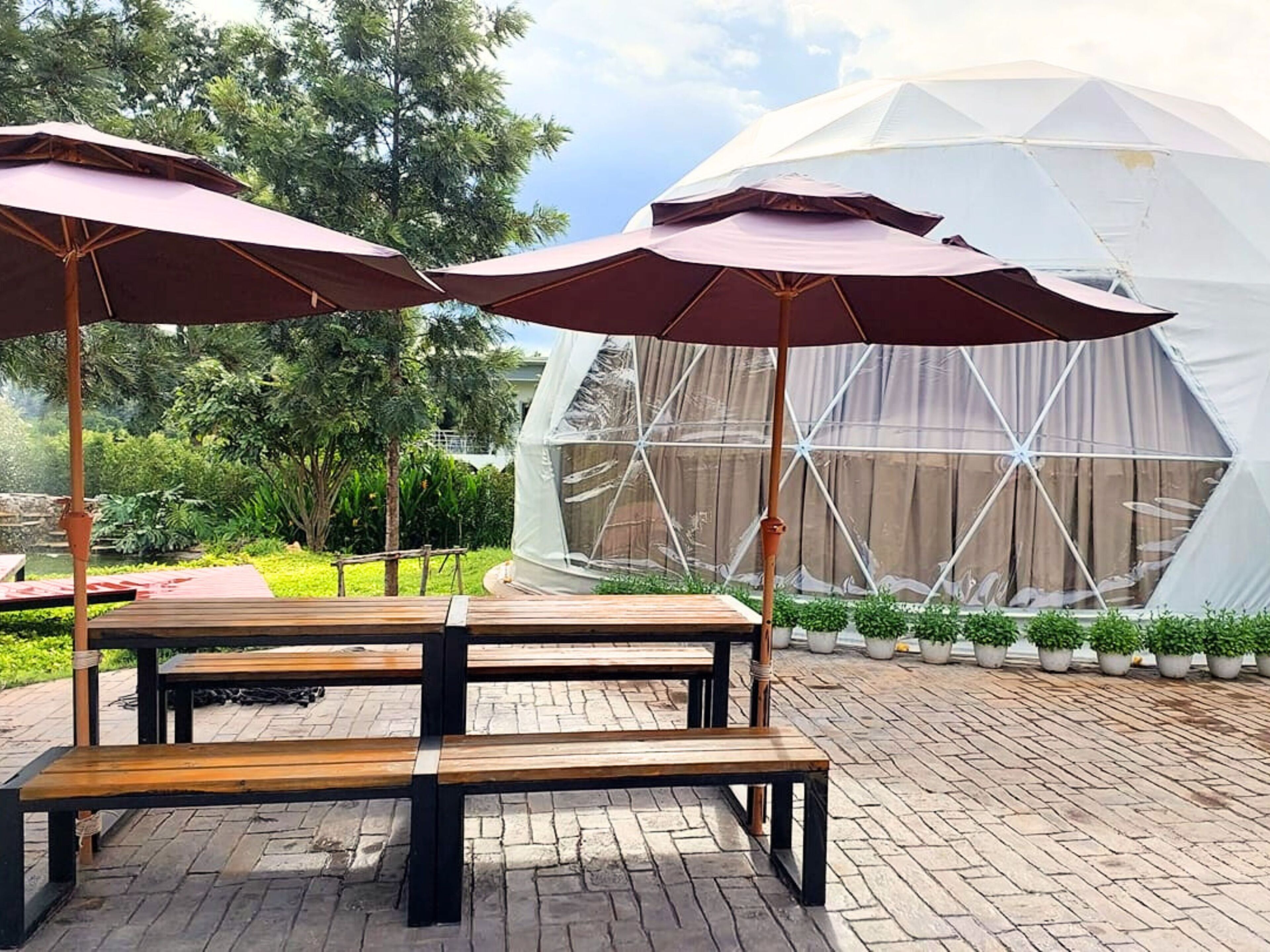 A gazebo with benches and umbrellas, a white dome structure, and a garden with potted plants.