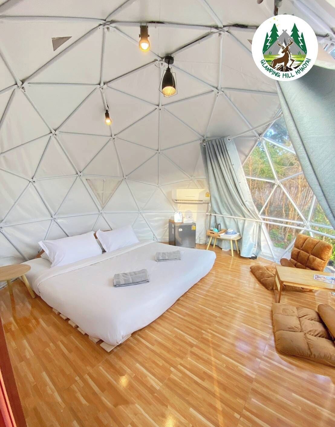 A spacious tent with a bed, a small table, and a chair.