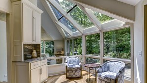 A sunroom with a sloped ceiling, large windows, and two patterned chairs. - The View From Up Here Changes Everything | Big Bear Pen (Highlands)