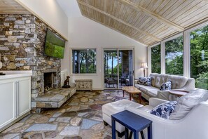 Una chimenea de piedra, un sofá blanco y un televisor montado en la pared.