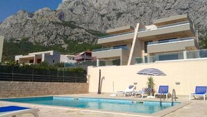 Ein modernes Gebäude mit Pool, Liegestühlen und Bergblick.