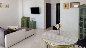 Ein modernes Wohnzimmer mit einer Couch, einem runden Tisch, einem Fernseher und einem Schrank.