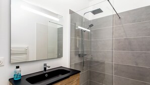 A modern bathroom with a black sink, wooden cabinet, and a glass shower enclosure. - New, quiet, comfortable 3-star Meublé de Tourisme apartment. (Saint-Pol-de-Léon)