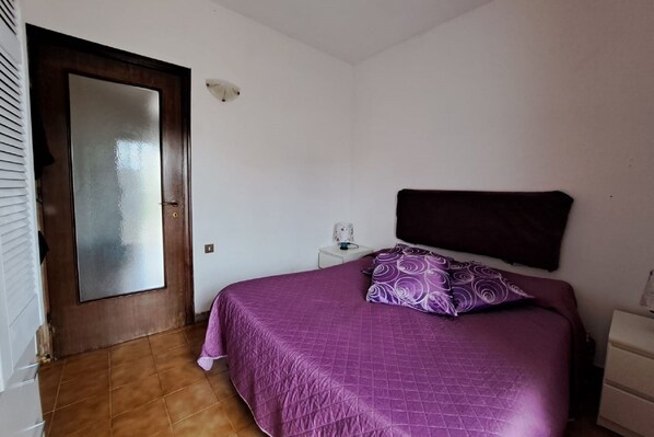 A bedroom with a bed, a nightstand, a dresser, and a door.