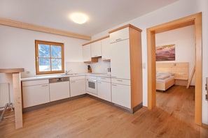 A compact kitchen with white cabinets, a wooden countertop, and a window.