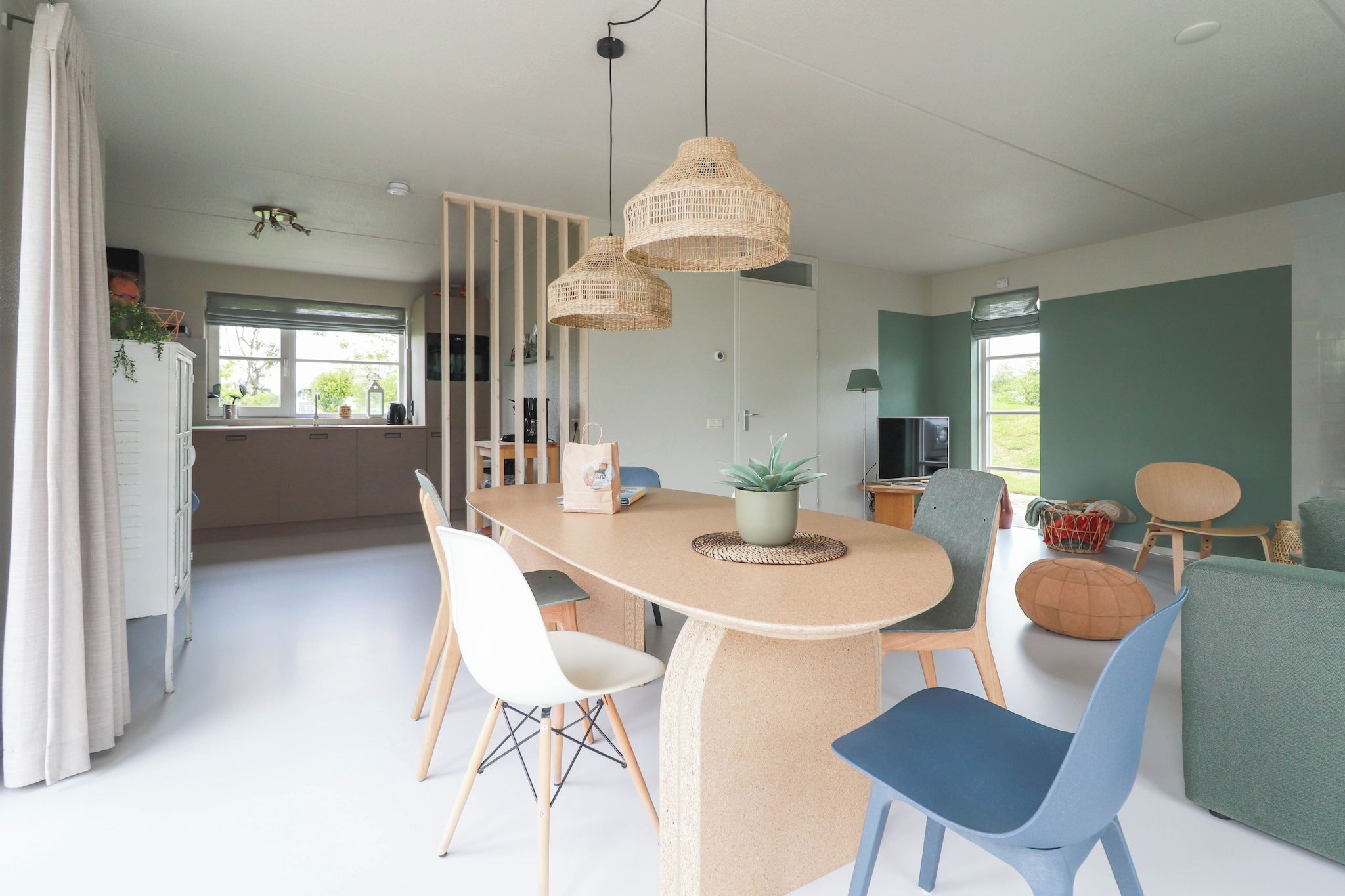 A modern dining area with a round table, chairs, and hanging wicker lamps.