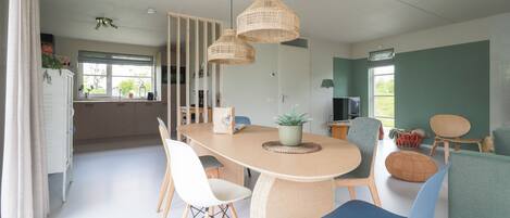 A modern dining area with a round table, chairs, and hanging wicker lamps.