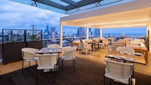 A rooftop terrace with dining tables and chairs, offering a city view. - Courtyard By Marriott Colombo (Colombo)