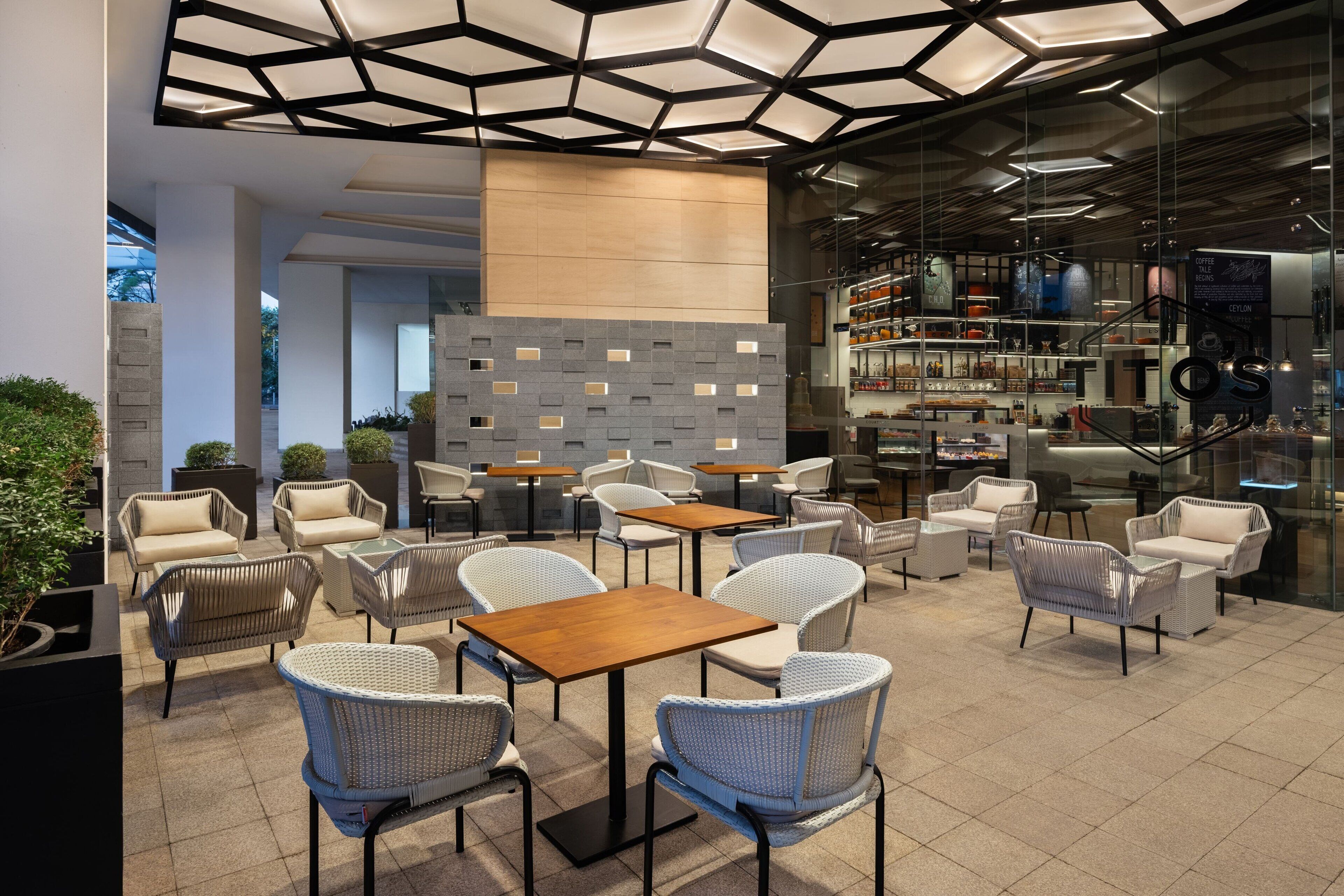 A modern cafe with wicker furniture, a coffee bar, and a glass wall.