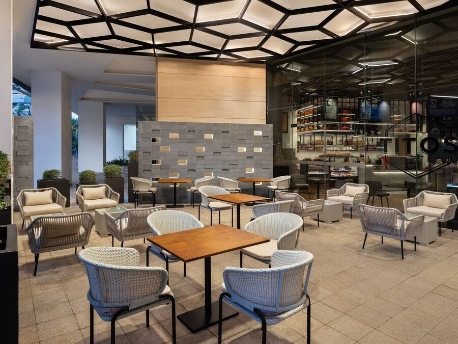 A modern cafe with wicker furniture, a coffee bar, and a glass wall.