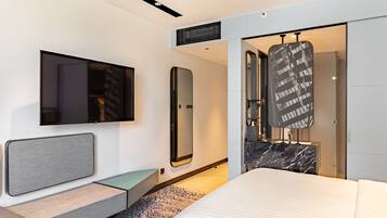 A modern hotel room with a large bed, a flat-screen TV, a mirror, and a wardrobe with a black and white patterned door.