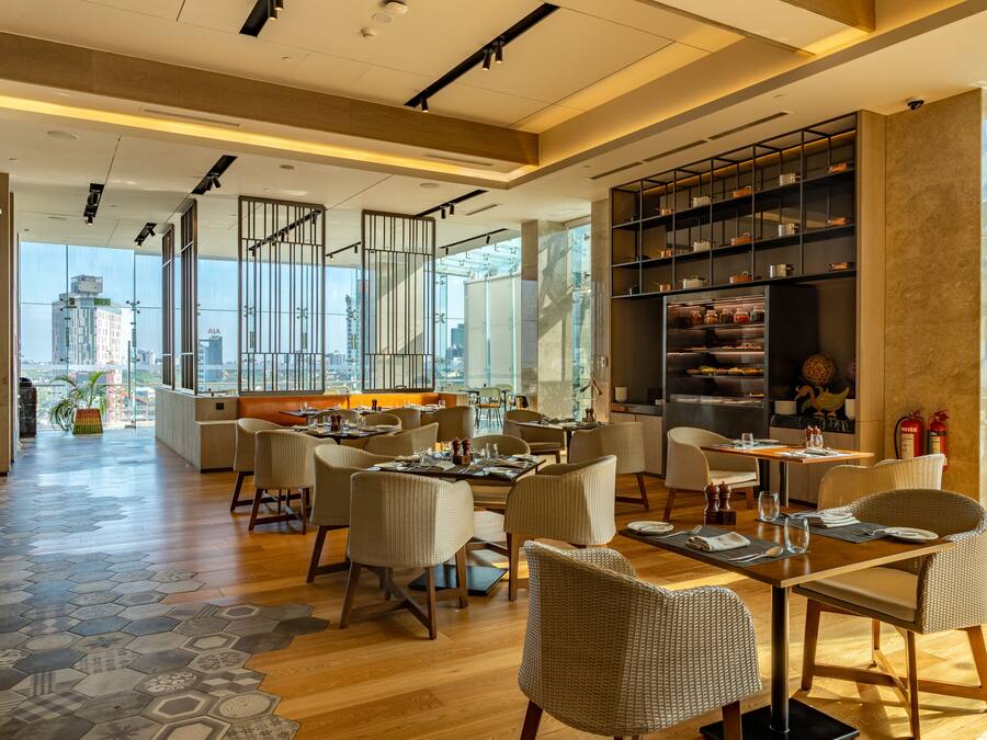 A modern restaurant with high ceilings, large windows, and a variety of seating arrangements.
