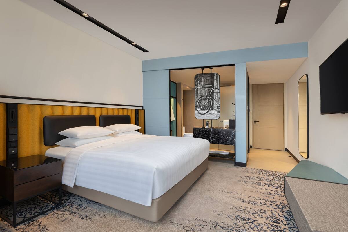 A modern hotel room with a large bed, a desk, and a television.