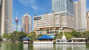 A modern hotel with a unique geometric facade, a prominent sign, and a view of a body of water with a traditional structure in the foreground. - Courtyard By Marriott Colombo (Colombo)