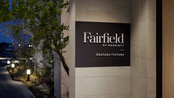 Señalización de Fairfield by Marriott en una zona urbana bien iluminada, con un camino pavimentado y áreas verdes.