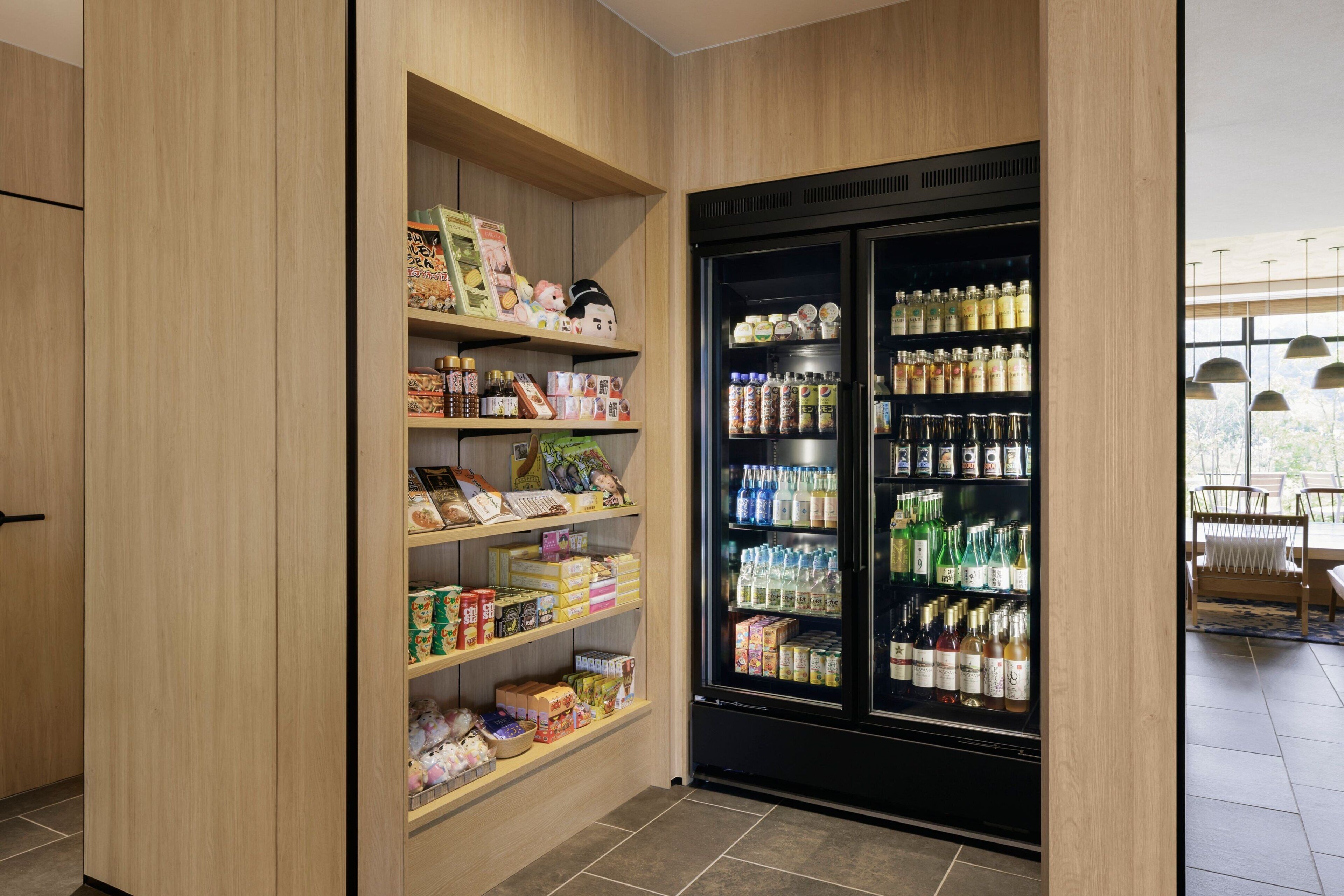 Una despensa bien organizada con estantes llenos de diversos alimentos y un refrigerador grande repleto de bebidas.