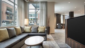 A modern living room with a sectional sofa, a round coffee table, and a large flat-screen TV. - Courtyard By Marriott Nanaimo (Nanaimo)