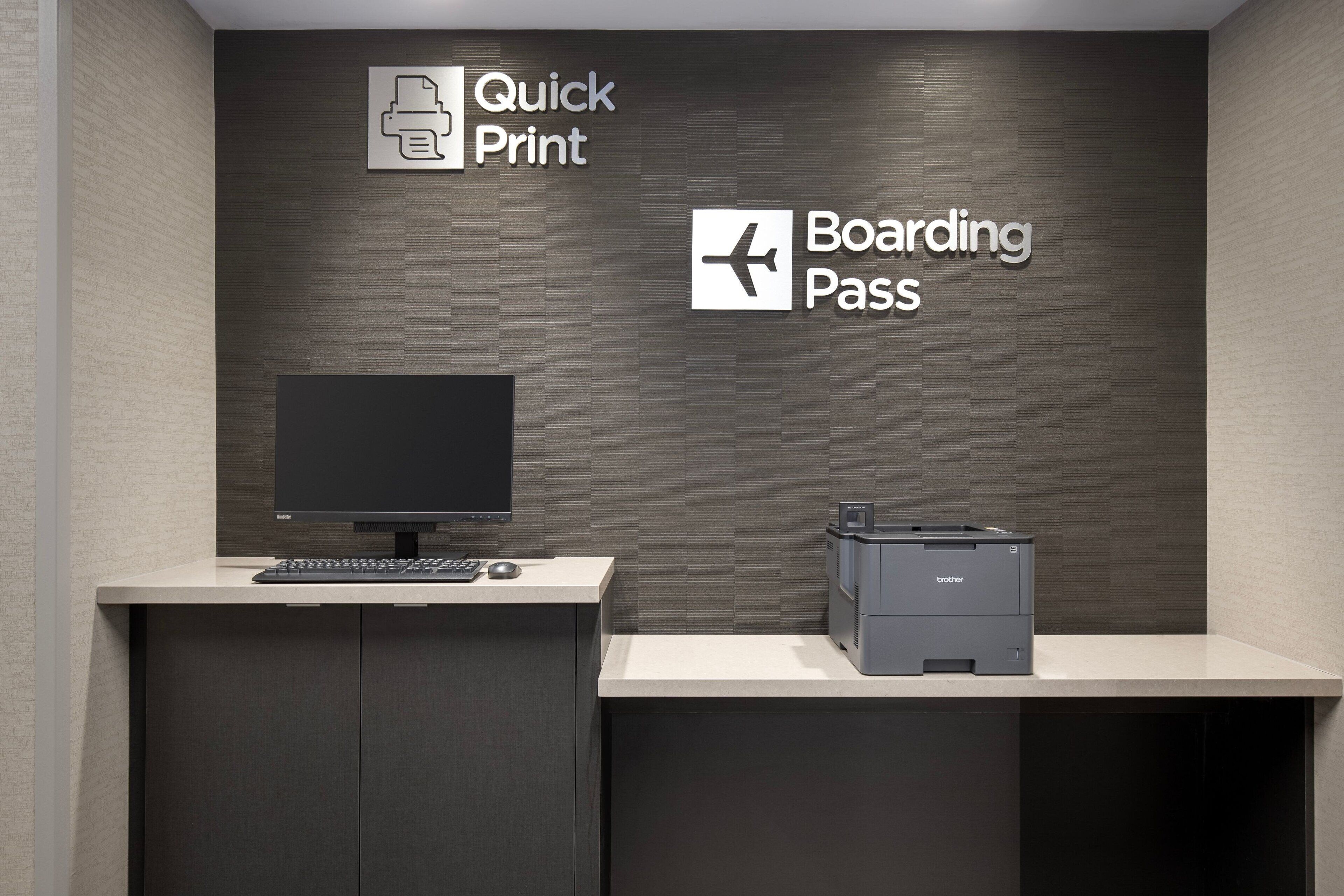 Balcão de recepção com monitor, teclado e impressora. Placas indicam 'Quick Print' e 'Cartão de Embarque'.