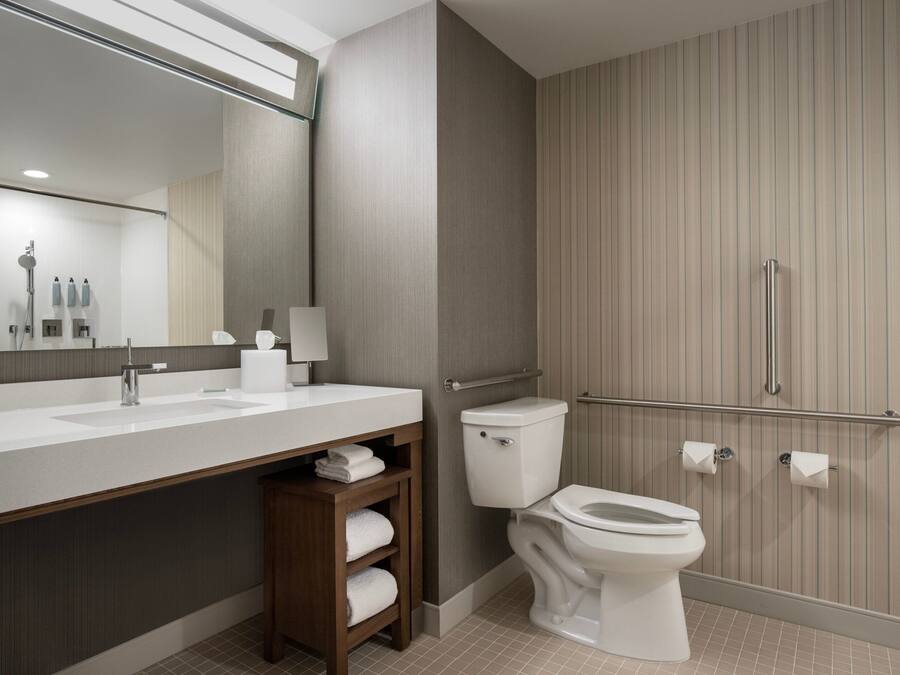 Un baño moderno con un espejo grande, un lavabo blanco, un inodoro y una zona de ducha.