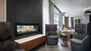 A modern lounge area with a fireplace, comfortable seating, and large windows. - Courtyard By Marriott Nanaimo (Nanaimo)