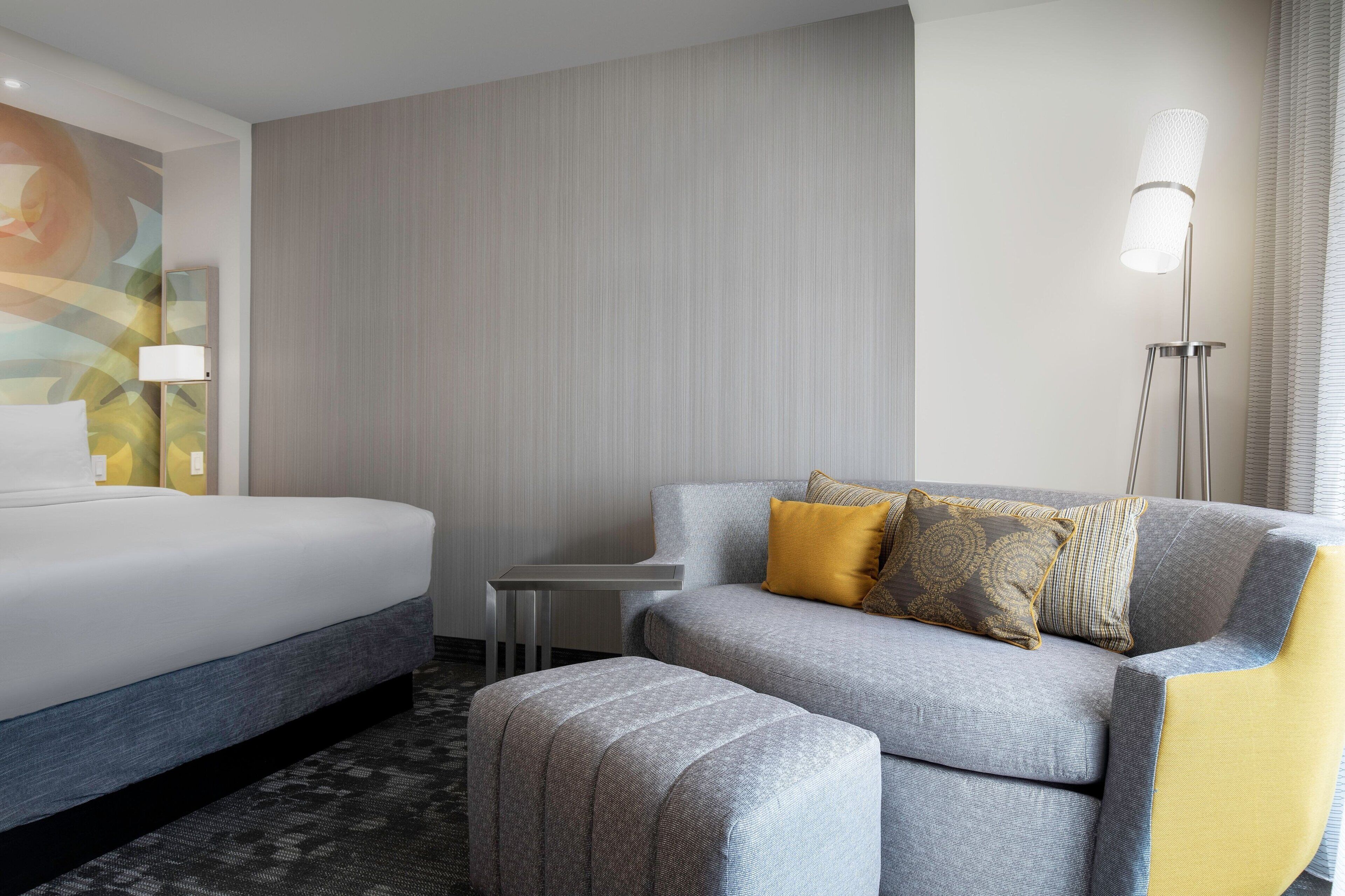 A hotel room with a bed, a sofa, and a small table.