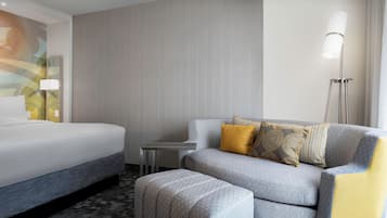 A hotel room with a bed, a sofa, and a small table.