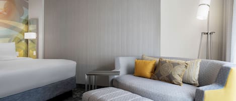 A hotel room with a bed, a sofa, and a small table.