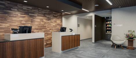 A reception area with a wooden reception desk, a white chair, and a wall with a patterned design.
