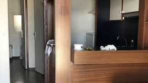 Une chambre d’hôtel avec un bureau en bois, un lavabo et un miroir.