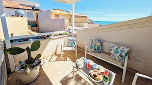 A rooftop terrace with a dining table, chairs, a sofa, and a potted plant. - The White House, terrace on the Mediterranean (Pozzallo)