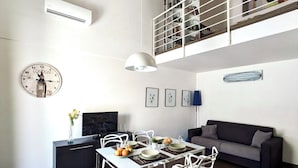 A modern living space with a dining area, a sofa, and a loft with a railing. - The White House, terrace on the Mediterranean (Pozzallo)
