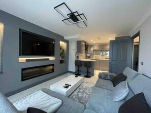 Un salon moderne avec un canapé gris, un téléviseur à écran plat et une cheminée.