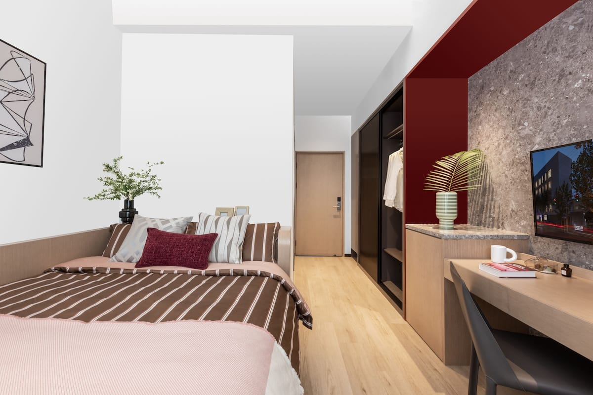 Una habitación de hotel moderna con cama, mesita de noche y zona de escritorio.