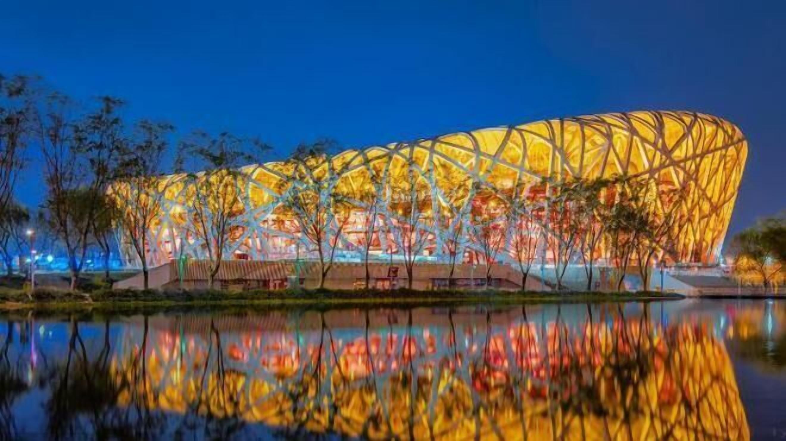A large, modern stadium with a distinctive, lattice-like roof structure.