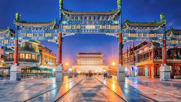 A traditional Chinese gate with intricate designs and a large building in the background.