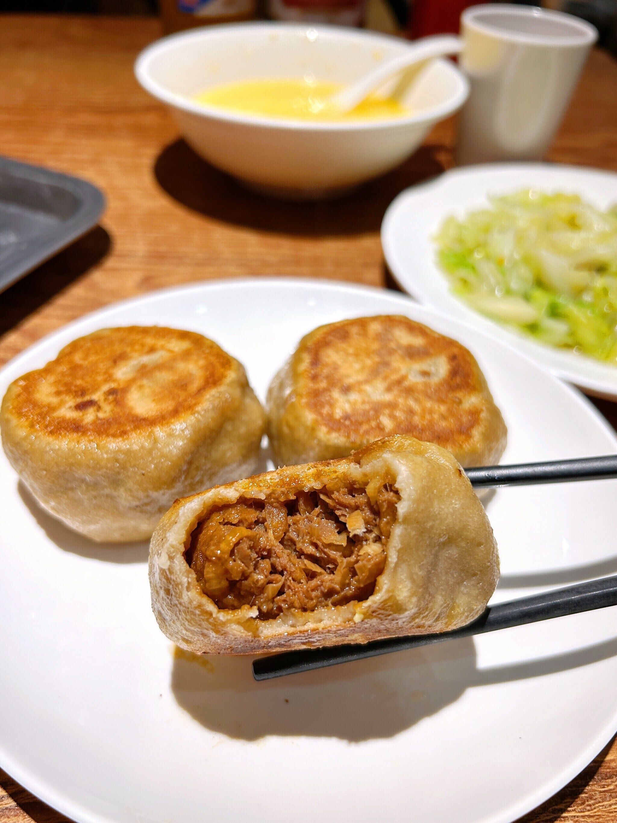 A plate with three dumplings, one cut in half to reveal the filling, on a white plate.