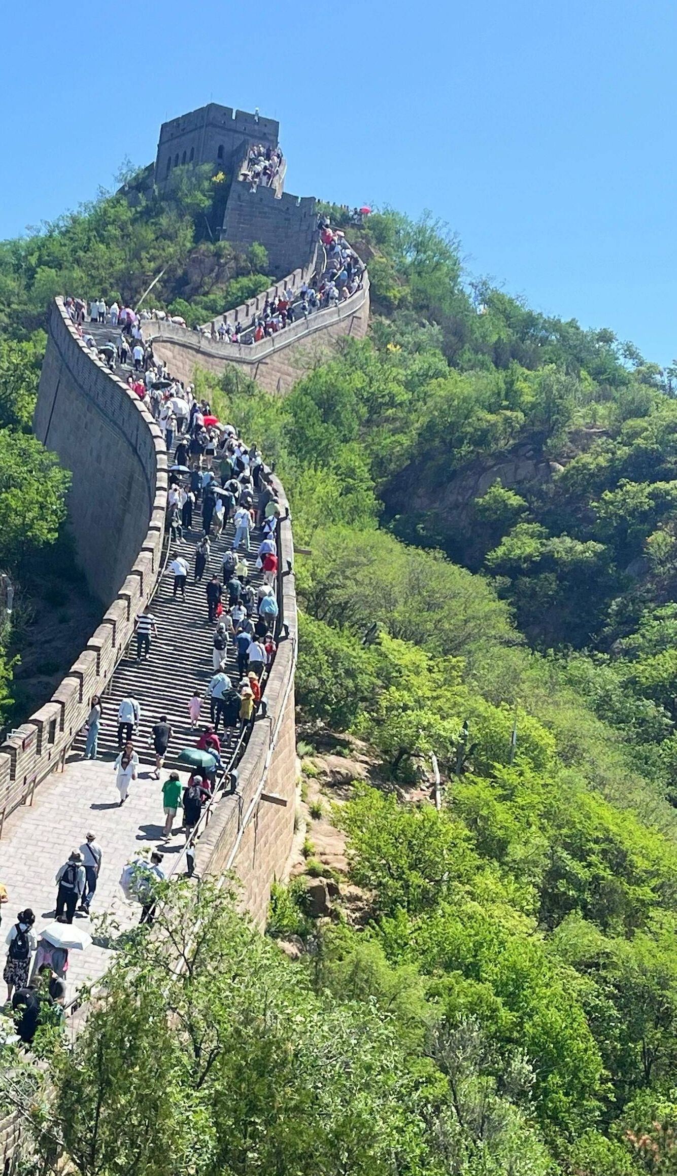 Une passerelle étroite et très fréquentée, construite sur un mur de pierre escarpé et incurvé, avec une tour de guet au sommet.