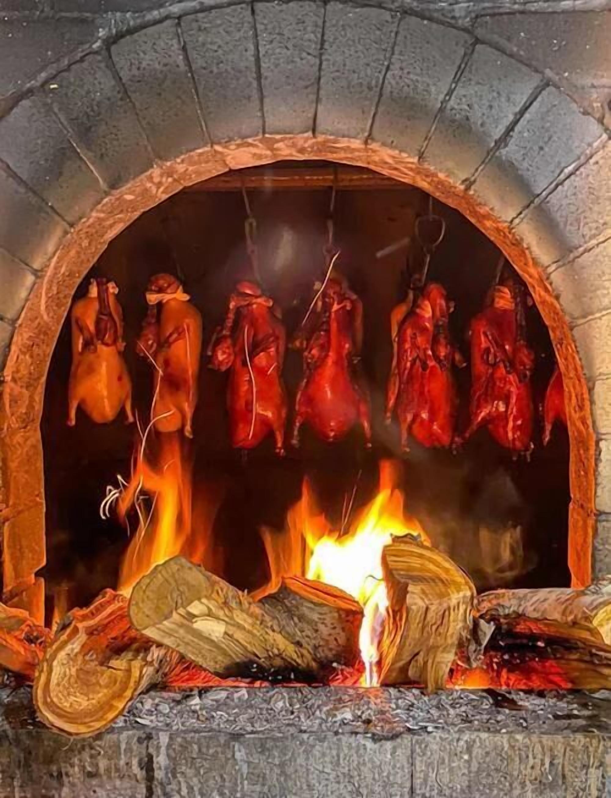 A stone fireplace with hanging meat.