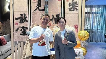Zwei Personen stehen vor einer Vitrine mit vertikalen Tafeln, die chinesische Schriftzeichen zeigen.