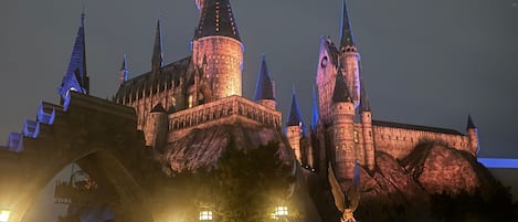 A large, illuminated castle-like structure with multiple towers and a bridge in the foreground.