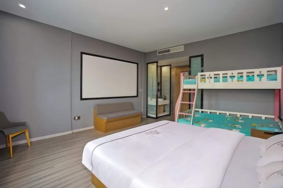 A hotel room with a bunk bed, a sofa, a chair, a large mirror, and a television.