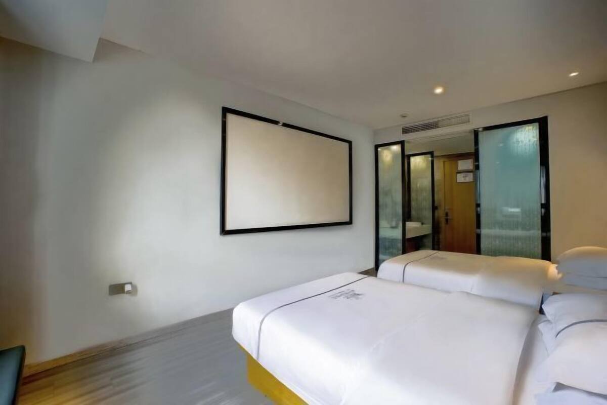 A hotel room with a bed, a mirror, and a door leading to a bathroom.