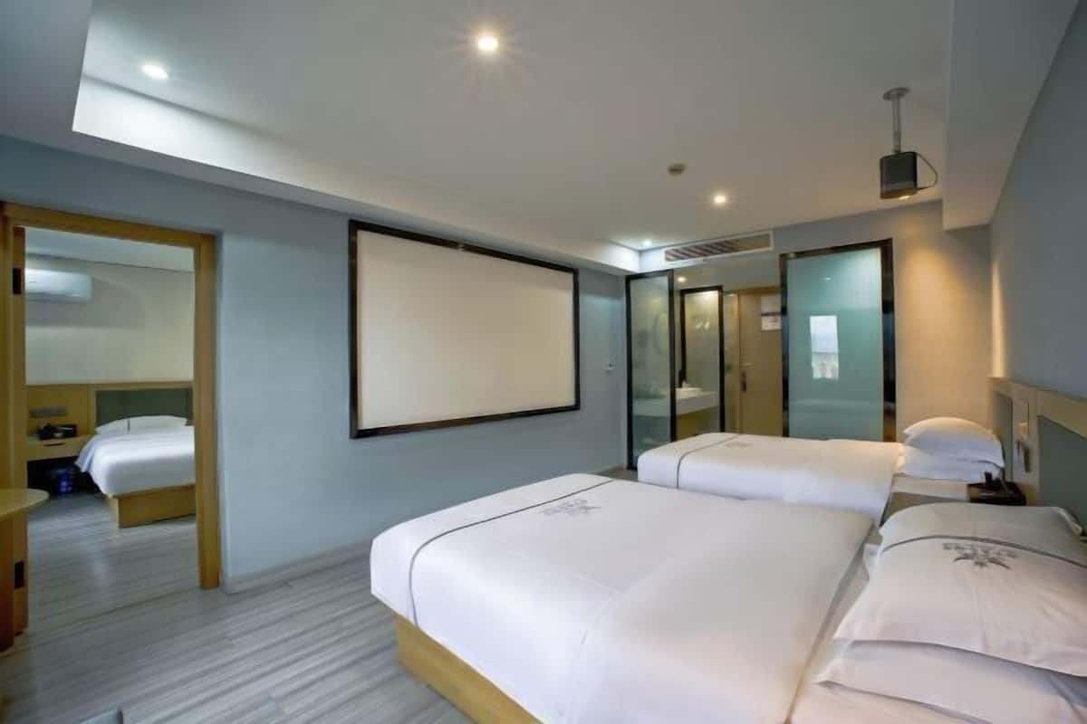 A modern hotel room with two beds, a large mirror, and a flat-screen TV.